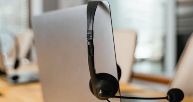 photo of a headset hanging over the corner of a laptop