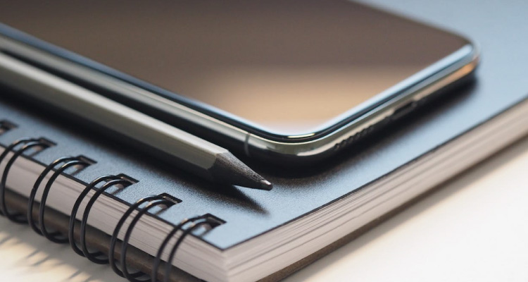 photo of an iphone with a pencil and notebook, depicting simple ease of use