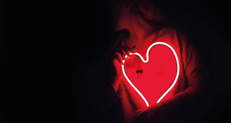 photo of a girl holding an illuminated sign of a heart