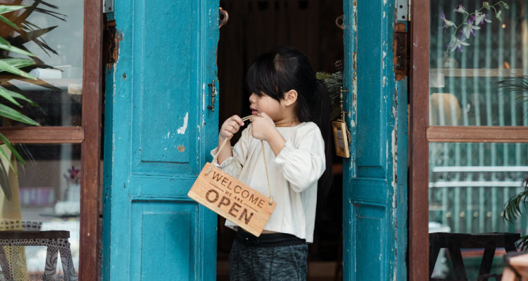 client onboarding - girl hanging a welcome sign on a door